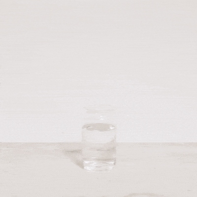Animated water jumping into liquid, forming a heart shape in a glass container.